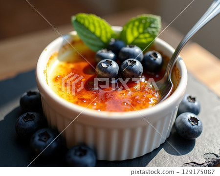 Classic Creme Brulee Dessert Topped with Fresh Blueberry and Mint Leaf 129175087