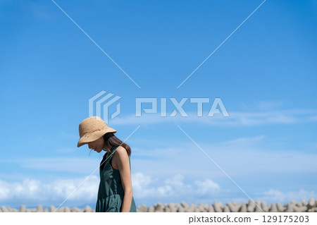 Woman walking along the beach in summer 129175203