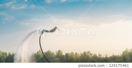 A man on a skateboard flies over the water like a superhero. Extreme sports. A man on a skateboard flies over the water like a superhero. Extreme sports. 129175461