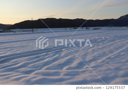 Snowfield lit by the setting sun Snowfield lit by the setting sun 129175537