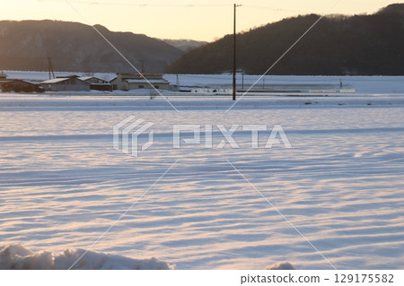 Snowfield lit by the setting sun Snowfield lit by the setting sun 129175582