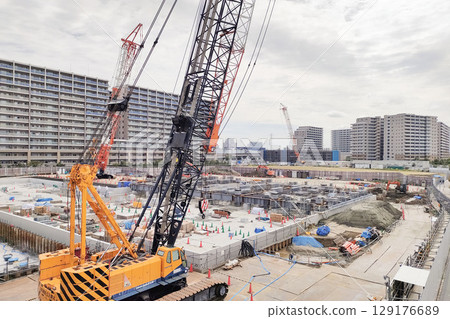 Large-scale construction site: Foundation work underway with large cranes in operation 129176689
