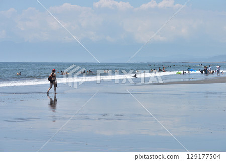 一名衝浪者沿著辻堂海灘的海岸線行走，尋找合適的海浪 129177504