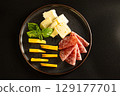 Cheese and olives served on a black plate 129177701