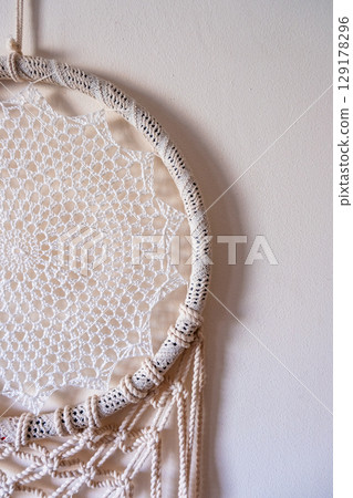 White dreamcatcher hanging on a white wall. Boho interior decor 129178296