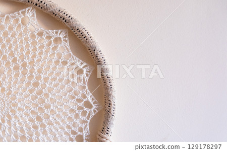 White dreamcatcher hanging on a white wall. Boho interior decor White dreamcatcher hanging on a white wall. Boho interior decor 129178297