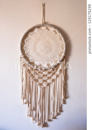White dreamcatcher hanging on a white wall. Boho interior decor 129178299