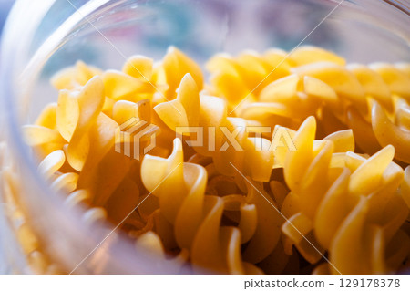 Close-up of uncooked fusilli pasta stored in the transparent glass jar Close-up of uncooked fusilli pasta stored in the transparent glass jar 129178378