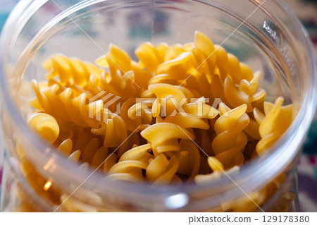 Close-up of uncooked fusilli pasta stored in the transparent glass jar 129178380