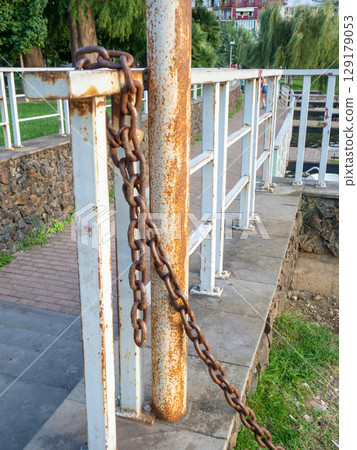 rusty chain is tied to a metal railing. Boat mooring. Reliable old chain. rusty chain is tied to a metal railing. Boat mooring. Reliable old chain. 129179053