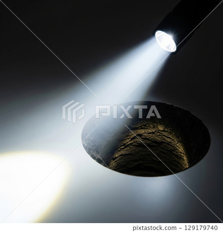 The beam of the flashlight illuminates a deep hole. The beam of the flashlight illuminates a deep hole. 129179740