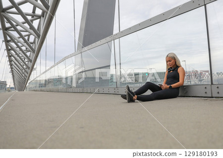 Young woman relaxing on a bridge after a fitness workout 129180193