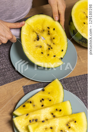 Close up shot of the cut watermelon with yellow flesh on ceramic plate 129180198