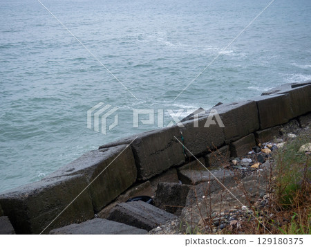 Old blocks of fortifications of the coast. Concrete structures on the shore. Protection against storms, waves and avalanches. Old blocks of fortifications of the coast. Concrete structures on the shore. Protection against storms, waves and avalanches. 129180375