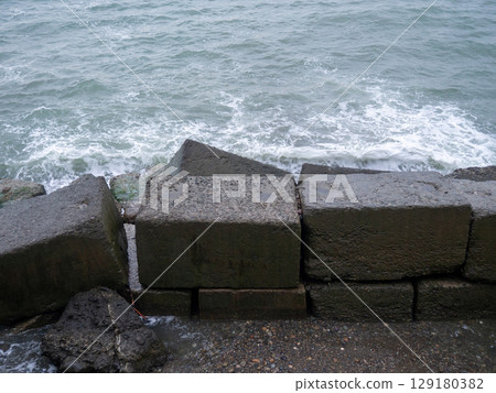 Old blocks of fortifications of the coast. Concrete structures on the shore. Protection against storms, waves and avalanches. 129180382