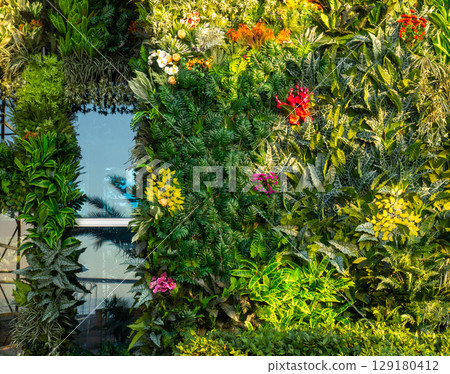 Facade of the building in greenery. Decorating works. The wall of the building is covered with artificial flowers and plants. Building reconstruction. 129180412