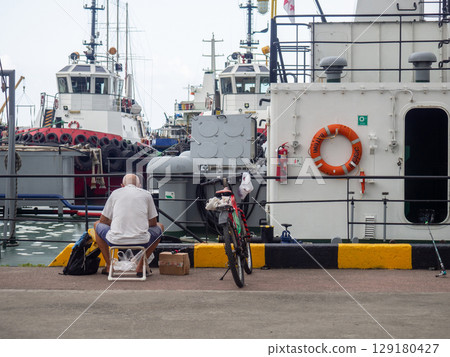 Fishermen near the ships. People at the pier. Favorite hobby. Fishing in the port. Family food. people with fishing rods 129180427