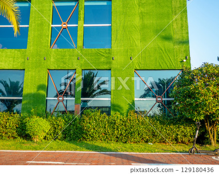 Facade of the building in green matter. Preparations for decorative work. Building reconstruction. Beautiful facade. 129180436