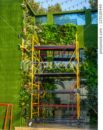 Facade of the building in green matter. Preparations for decorative work. Building reconstruction. Beautiful facade. 129180440