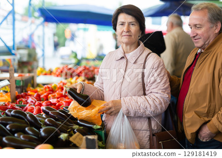 Aged man and woman customers buying vegetables in open-air market Aged man and woman customers buying vegetables in open-air market 129181419