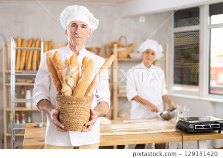 Elderly male seller showing assortment of bakery 129181420