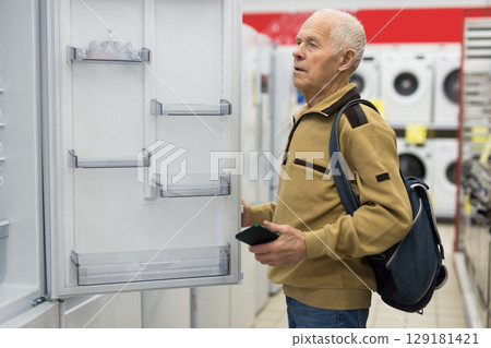 senor man pensioner buying fridge in showroom of electrical appliance store 129181421