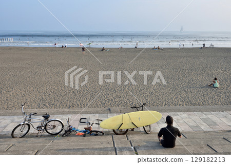 A surfer looking out to sea from the stairs of Katase Nishihama 129182213