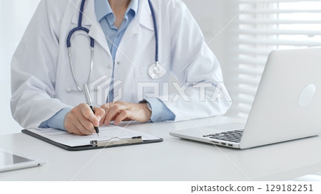 Female doctor documents patient information while working with digital devices at workplace in office. Medicine and healthcare concept Female doctor documents patient information while working with digital devices at workplace in office. Medicine and healthcare concept 129182251