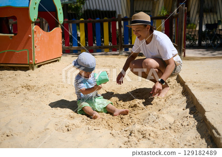 Mother and Child Enjoying Playtime in a Sunny Park Sandbox Playground 129182489