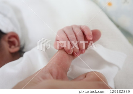 Newborn baby's tiny hand holding mother's hand 129182889