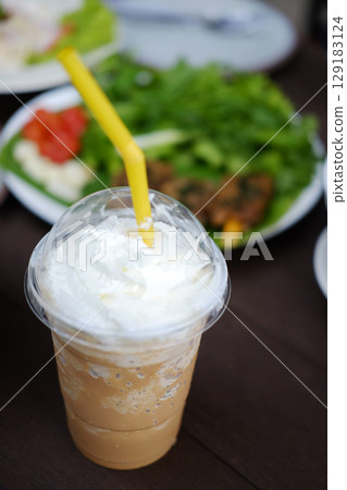 Ice latte shake coffee with whipped cream in plastic glass with traditional Thai food. Copy space of vertical 129183124