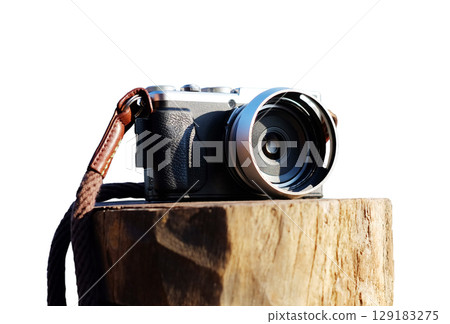 A vintage black and silver mirrorless camera on tree stump isolated on white background with clipping path A vintage black and silver mirrorless camera on tree stump isolated on white background with clipping path 129183275
