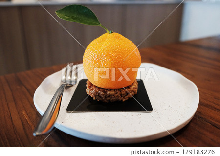 Homemade fresh orange cake and cream on chocolate Hazelnut on black plate and wooden table 129183276