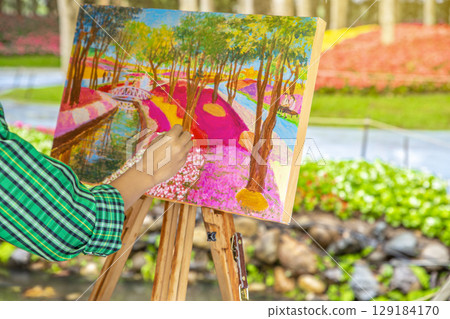 The artist paints and sketch a picture outdoors in the early sunny morning. Painting in nature. The artist paints and sketch a picture outdoors in the early sunny morning. Painting in nature. 129184170
