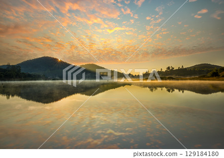 The riverside village and mountains reflect the water in the misty morning at Lake Wolfgang, Austria. 129184180