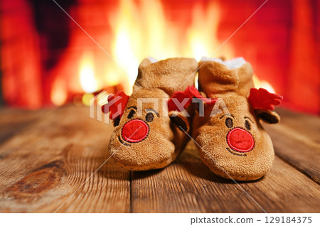 small fleece boots with the head of a Christmas deer in front of a fireplace small fleece boots with the head of a Christmas deer in front of a fireplace 129184375