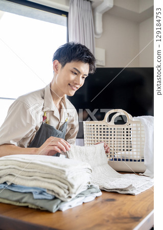 A househusband carefully folding laundry 129184753