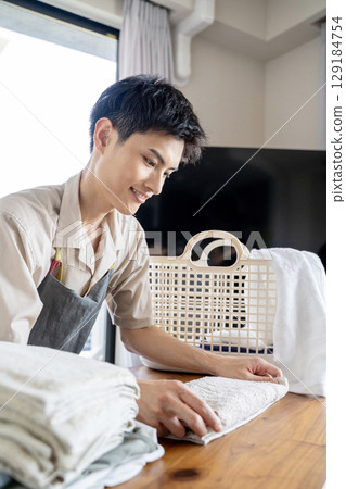 A househusband carefully folding laundry 129184754