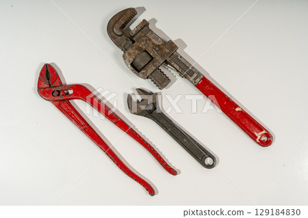 Adjustable wrench, pipe wrench and slip joint pliers lying on white background 129184830