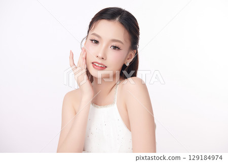 A beautiful young Asian woman with clean, fresh skin against a white background. Skincare, facial treatment, cosmetology, beauty, and spa. An elegant portrait of an Asian woman. 129184974