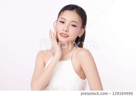 A beautiful young Asian woman with clean, fresh skin against a white background. Skincare, facial treatment, cosmetology, beauty, and spa. An elegant portrait of an Asian woman. A beautiful young Asian woman with clean, fresh skin against a white background. Skincare, facial treatment, cosmetology, beauty, and spa. An elegant portrait of an Asian woman. 129184999