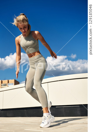 Young woman exercising outdoors in sportswear on a sunny day Young woman exercising outdoors in sportswear on a sunny day 129185046