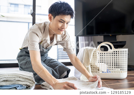 A househusband carefully folding laundry 129185129