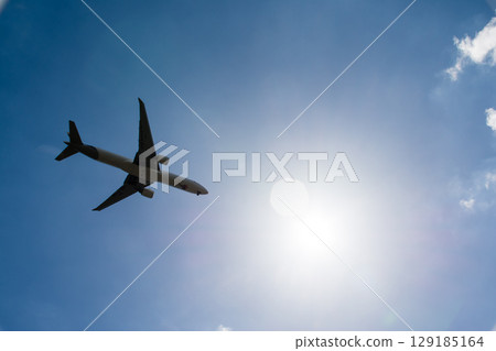 一架客機在倫敦郊區希斯洛機場附近耀眼的陽光和藍天下飛過 一架客機在倫敦郊區希斯洛機場附近耀眼的陽光和藍天下飛過 129185164