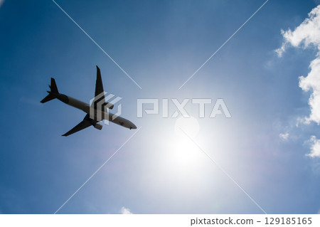 一架客機在倫敦郊區希斯洛機場附近耀眼的陽光和藍天下飛過 一架客機在倫敦郊區希斯洛機場附近耀眼的陽光和藍天下飛過 129185165
