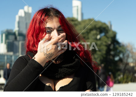 Young woman covering her mouth with tattooed hand, laughing in buenos aires 129185242