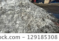 Large pile of dirty, melting snow in an urban or industrial area. 129185308