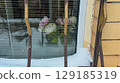 Winter window with fresh snow and blooming flowers behind blinds, symbolizing warmth and longing for spring. 129185319