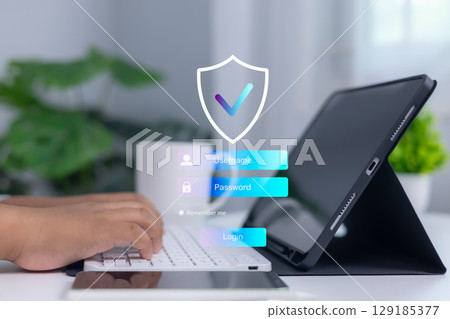 Person logging into secure system on digital tablet with shield and checkmark icon, representing cybersecurity, data protection, and confidential access in modern business technology. 129185377