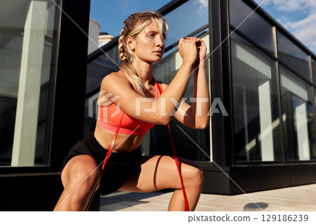 Fitness woman exercising with resistance band in outdoor urban setting 129186239